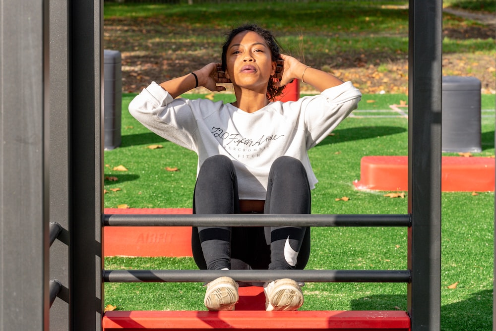 mujer con camisa blanca de manga larga y pantalón negro realizando Crunches